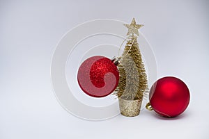 Christmas toy, two shiny red balls and a golden Christmas tree. New Year. On a gray background