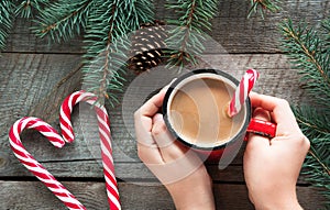 Christmas tradition drink. Mug hot coffee with milk, red candy cane on the wooden background. New Year. Holiday card. Rustic style