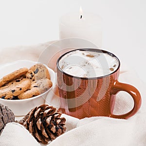 Christmas traditional hot drink cocoa with marshmallow and cookies with chocolate drops in red cup, cones, candle