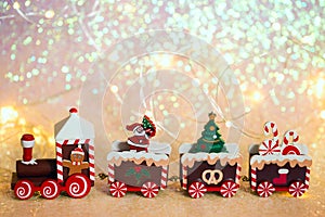 Christmas train on a shiny background. Toy wooden train with gifts, Santa, parcels and Christmas tree