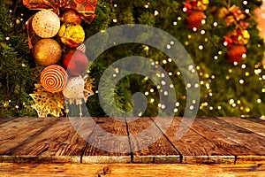 Christmas tree background with decoration and blurred light bokeh with empty dark wooden deck table for product montage.