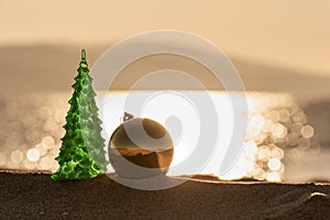 Christmas tree and ball on the beach and blurred sea in background. Happy New Year and Merry Christmas greeting card