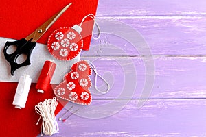 Christmas tree and ball ornaments, scissors, thread, needle, red and white felt pieces on a wooden background with blank place