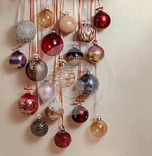 Christmas tree balls in brown burgundy gold black color on a light wall. Balloons hang on a ribbon with a bow.