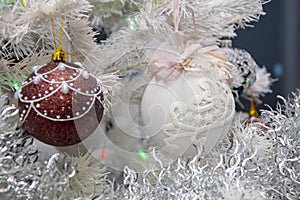 Christmas tree balls hang on the white artificial Christmas tree, holiday decorations.