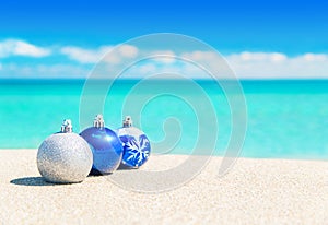 Christmas tree blue and silver balls decorations on beach sand