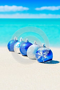 Christmas tree blue and silver balls decorations on beach sand