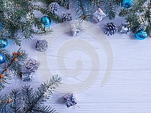 Christmas tree branch, ball, gift, cone on white wooden background