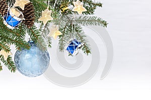 Christmas tree branch with blue glass ball, decorative drums toys and star light garlands on white background