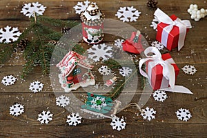 Christmas tree branch with gifts, gingerbread, snowman candle and decorations snowflakes on the wooden background.