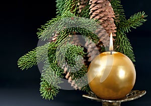 Christmas tree branch with golden burning candle
