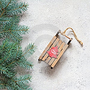 Christmas tree branch on a gray background, festive mood, gift season. Decorative wooden sled for decoration , toys.
