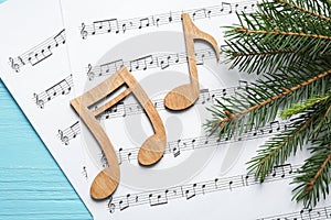 Christmas tree branch, notes and music sheets on wooden table, flat lay