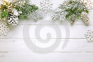 Christmas tree branch with pine cone in snow and retro style clock on a white wooden background. Winter or Christmas festive