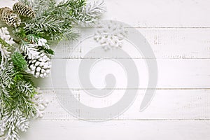 Christmas tree branch with pine cone in snow and retro style clock on a white wooden background. Winter or Christmas festive