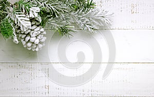 Christmas tree branch and pine cone in snow on a white wooden background. Winter festive concept. Flat lay, copy space