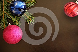 Christmas tree branch with pink, blue and red wavy ball on a dark background