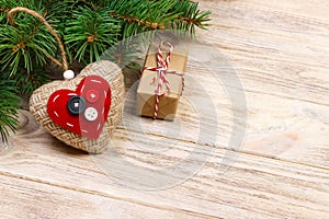 Christmas tree branch with red gift box and red hearts on wooden table. Top view with copy space