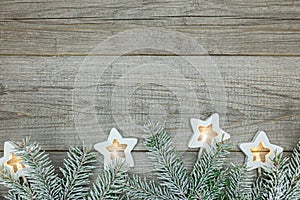 Christmas tree branches and glowing star lights on natural wooden boards