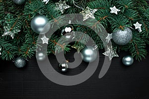 Christmas tree branches with New Year`s decor and stars on a dark wooden background