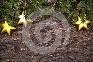 Christmas tree branches with star baubles and lights on wooden background.