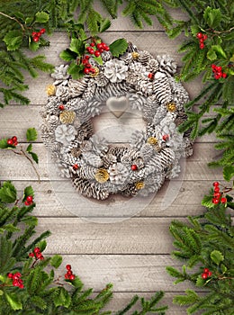 Christmas tree branches, wreath decoration and red berries on grey wooden background