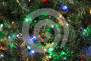 Christmas tree with bright string lights, closeup. Bokeh effect