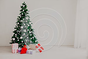 Christmas tree with Christmas gifts in white room