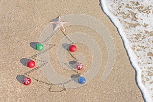 Christmas tree contour with decorations, star and wave on the beach