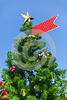 A Christmas tree crowned with a star tree-topper and red ribbon