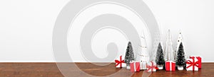 Christmas tree decor with red and white gifts on a wood shelf against a white wall banner background