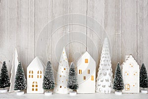 Christmas tree decor and white houses on a shelf against a rustic grey wall