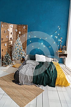 Christmas tree decorated with blue balls and dried oranges. wood in the interior with screen, light floor and blue wall