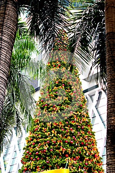 Christmas tree decorated with many small red balls and yellow ribbons in the daytime