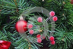 A Christmas tree decorated with red festive balls in a pot