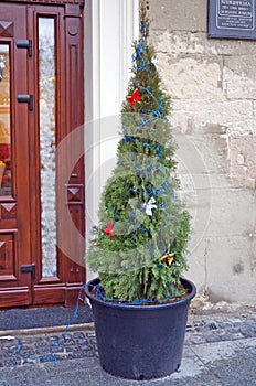 A Christmas tree decorated with red festive balls in a pot
