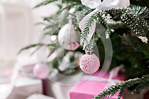 Christmas tree decorated with toys in silver and pink color. In it we see the balloons with of ribbons and lights