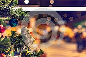 Christmas tree decoration foreground with bell on unfocused festive background bokeh garland lights inside shopping mall in