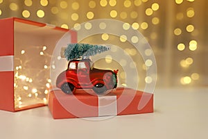 Christmas tree decoration a red car with a Christmas tree on the lead stands on a gift box. Background is a defocused