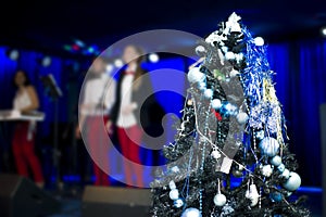 Christmas tree in decorations. Celebratory concert in blurred background