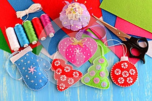 Christmas tree decorations crafts. Felt pink heart, red and green Christmas tree, blue mitten, red ball on wooden background