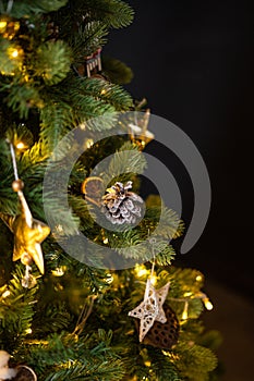Christmas tree decorations in a dark key, garland and golden wood toys, pine cones and lights.