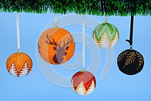 Christmas tree decorations hanging on ribbons from a branch of an artificial tree