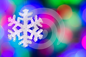 Christmas-tree decorations - snowflake against blurred garland lights background.