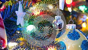 Christmas tree decorations. Yellow, shiny finish, orb with blue circles, glows, surrounded by bright vibrant multicoloure lights.