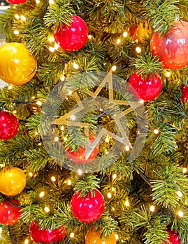 Christmas tree detail, baubles, lights and golden star hanging close up