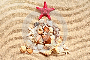 Christmas tree with different seashells on the sea sand. Creative Christmas background.