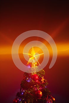 Christmas tree with festive lights, orange background with mist