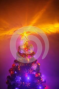 Christmas tree with festive lights, purple background with smoke