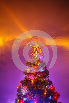 Christmas tree with festive lights, purple background with smoke